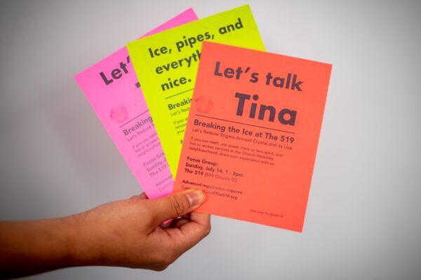 A hand holding flyers printed in colourful paper