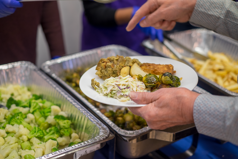 A hand holding a plate with food.