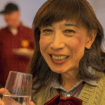 An older adult holding a glass of water and smiling