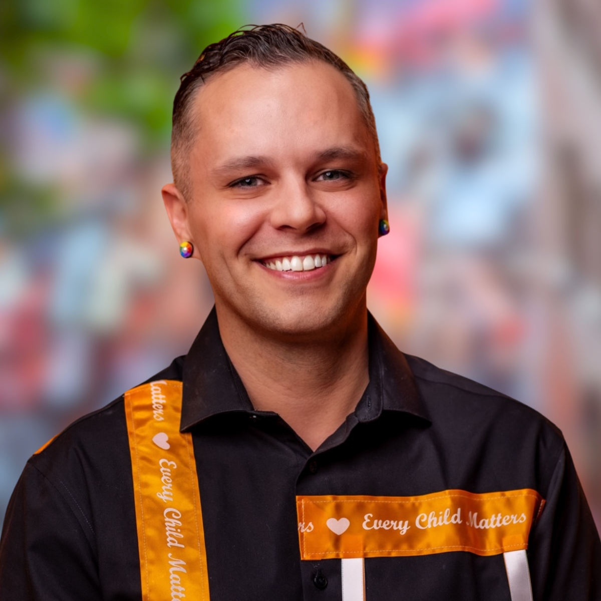 Jaris Swidrovich, Member of the Board. He is wearing a black shirts with an orange strip across with white text "Every child matters".